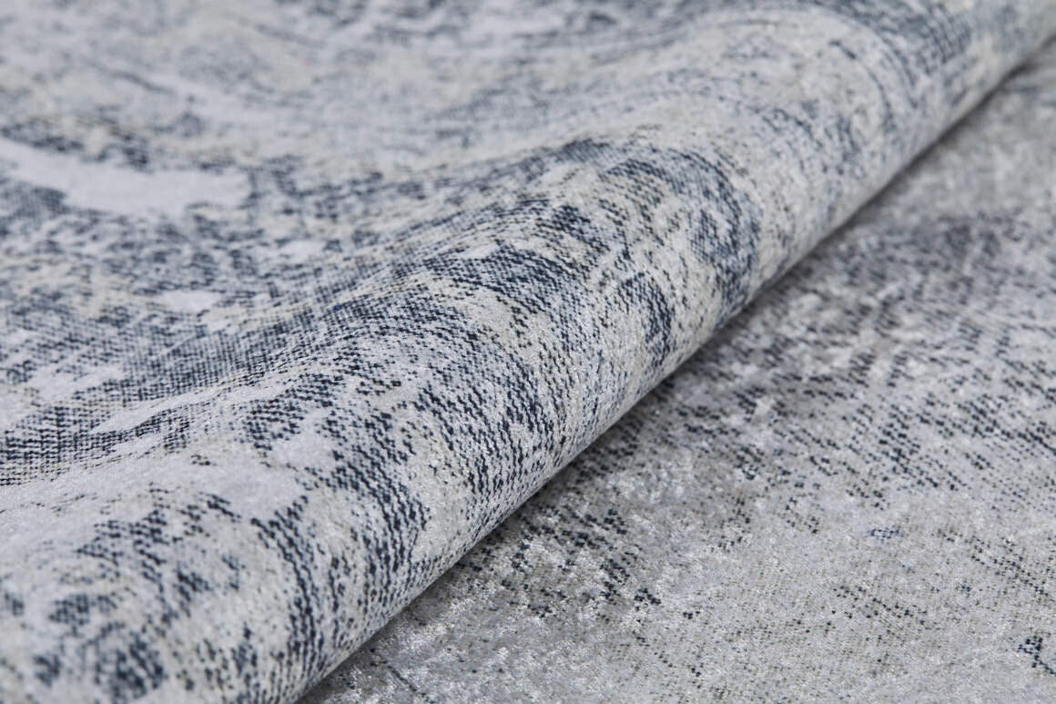 A close-up of the Faint Memories - Washable Rug - JR1437 highlights its dense woven fibers, abstract patterns, and a durable gray and off-white surface in textured gray-anthracite tones.