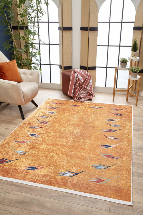 Load image 1 in gallery view. A modern living room featuring the Floral Mosaic - Washable Rug - JR1720 in orange, a beige armchair with pillows, potted plants, a small plant table, and a striped pouf by tall arched windows—ideal for high-traffic spaces.
