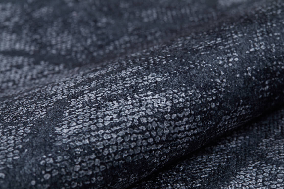 Close-up of the Geometric Gems - Washable Rug - JR1342, featuring a dark gray and black textured pattern with a snakeskin-like design—soft, subtly folded, and perfect for high-traffic areas.