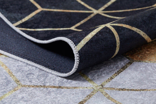 Load image 1 in gallery view. A close-up of the Geometric Harmony - Washable Rug - JR1271, featuring a folded corner, black and gray-anthracite colors with gold lines, geometric patterns, and visible edge stitching.