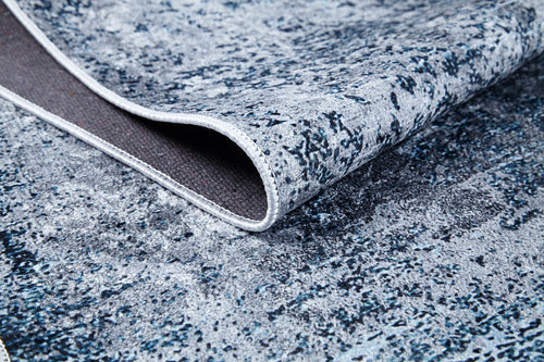 Load image 1 in gallery view. A close-up of the Imperial Lace - Washable Rug - JR1607 shows its textured abstract pattern in blue, gray, and white, with a lifted corner revealing the washable underside and stitched edge—perfect for high-traffic areas.