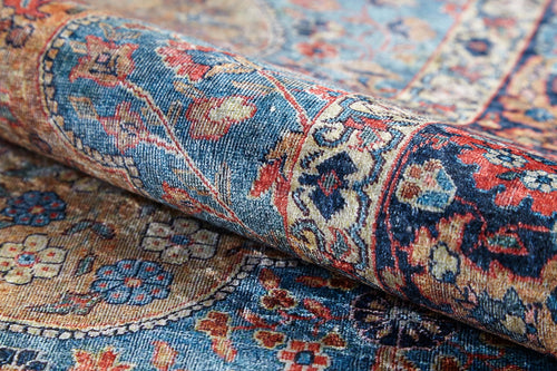 Load image 1 in gallery view. A close-up of the Imperial Weave - Washable Rug - JR1969, rolled to showcase its vintage Persian-inspired blue design with intricate floral patterns in shades of blue, red, cream, and gold—durable for high-traffic areas.