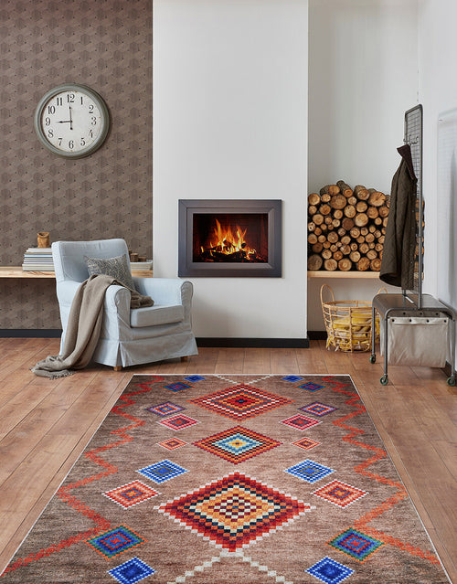 Load image 1 in gallery view. A cozy living room features the Kilim Kingdom - Washable Rug - JR1536 in multicolor, a gray armchair with a blanket, wall clock, modern fireplace with stacked firewood, basket, and beautiful hardwood floors.