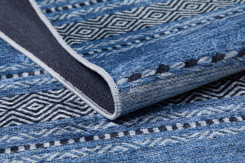 Load image 1 in gallery view. A close-up of the Layered Lines - Washable Rug - JR1545 shows its geometric blue patterns, a slightly folded edge revealing the underside and stitching—ideal for high-traffic areas.