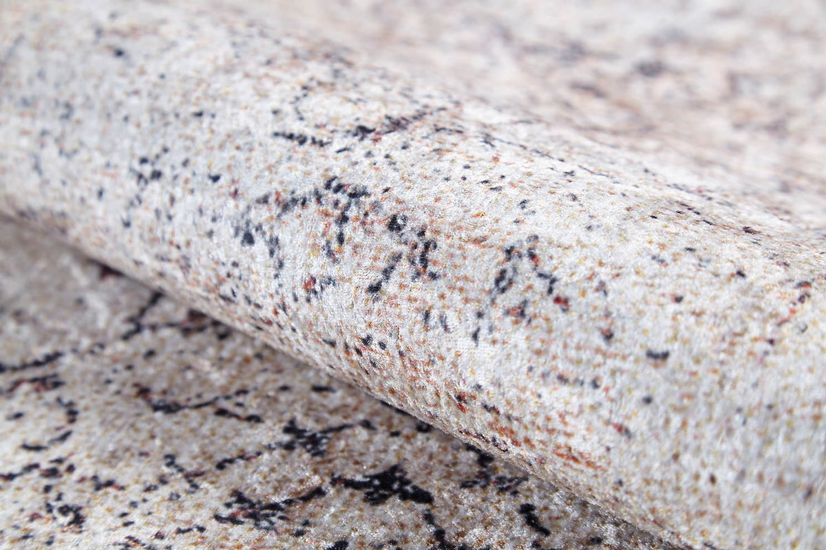 A close-up of Misty Mosaic - Washable Rug - JR1690 reveals its beige, granite-like texture with brown, black, and gray speckles—ideal for those wanting allergy-sensitive rugs in cream and beige tones.