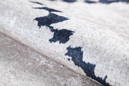 Load image 1 in gallery view. Close-up of the Moroccan Mosaic - Washable Rug - JR1655 in light gray-anthracite, featuring a soft, textured surface and abstract dark blue and black patterns; shown partially rolled to display its plush material—ideal for high-traffic areas.