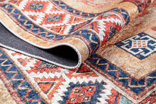 Load image 1 in gallery view. A close-up of the Navajo Nights - Washable Rug (JR1758) featuring vibrant geometric and diamond patterns in red, blue, orange, and beige. One corner is curled up to show the dark backing—perfect for high-traffic areas.