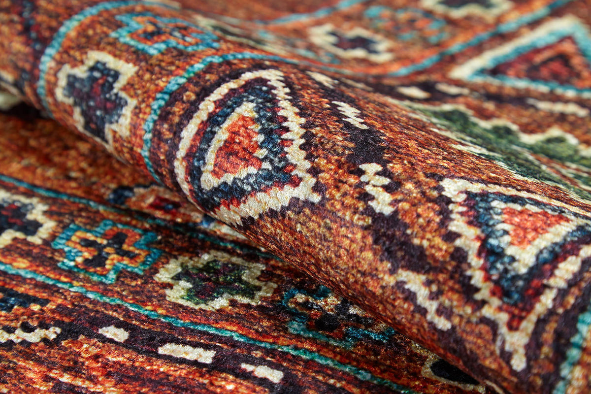 A close-up of the Nomadic Oasis - Washable Rug - JR5086, featuring a rolled flat weave with intricate geometric and floral patterns in brown, blue, orange, green, and white. The textured fabric is clearly visible.