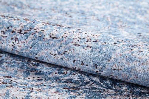Load image 1 in gallery view. A close-up of the Old World Charm - Washable Rug - JR1606, rolled up to show its blue and gray stone-like abstract texture—ideal for high-traffic areas.