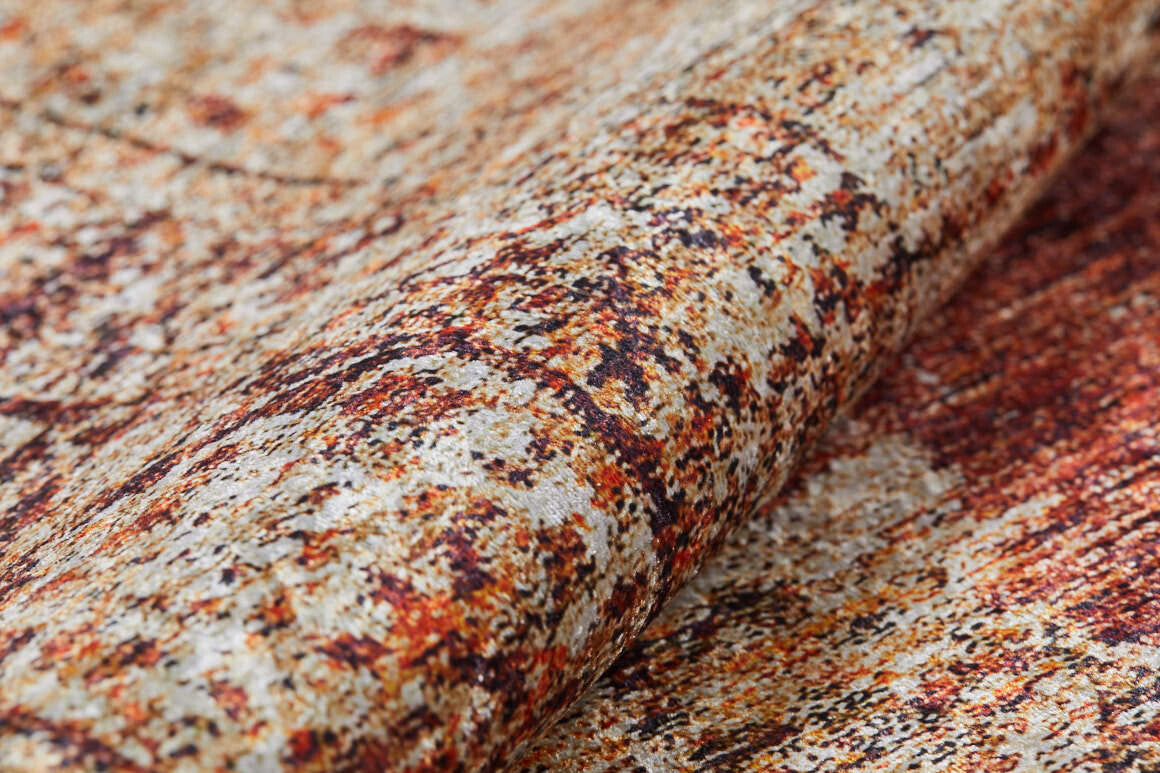 Close-up of the Ornate Grace - Washable Rug - JR1009, showing its textured, mottled pattern in brown, orange, beige, and cream. The slightly folded fabric adds to its abstract, weathered look—perfect for high-traffic spaces.