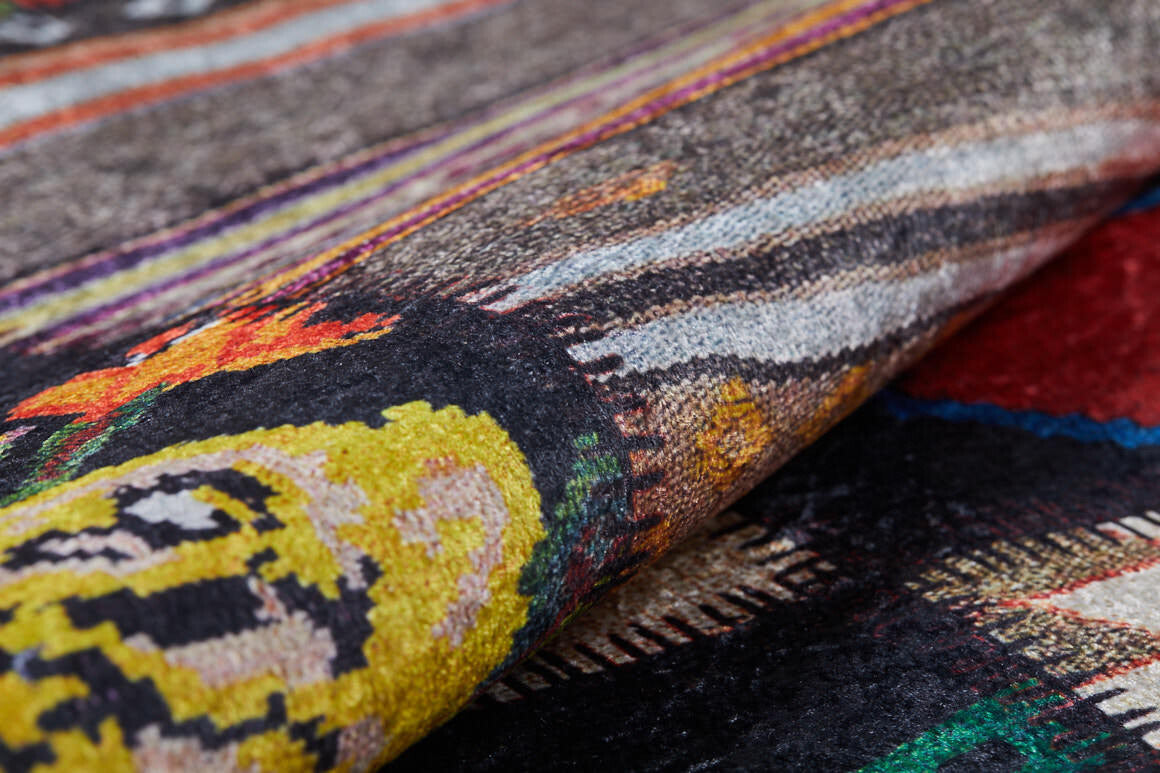 A close-up of the Petal Paradise - Washable Rug - JR315, partially rolled to showcase its vibrant yellow, black, red, and multicolored patterns—an ideal stylish addition for high-traffic spaces.