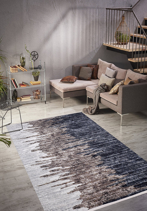 Load image 1 in gallery view. A modern living room features a gray sectional sofa, assorted pillows, light wood floors, and a metal shelf with plants. The space is anchored by the Pixelated Paradise - Machine-Washable Rug JR902 in bronze and brown tones, perfect for allergy-sensitive homes.