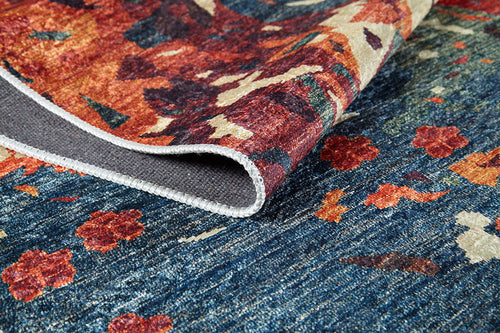 Load image 1 in gallery view. A close-up of the Psychedelic Splash - Machine-Washable Rug (JR5096), featuring vibrant abstract floral patterns in red, orange, and blue. A folded corner reveals its texture and unfinished edge—ideal for high-traffic areas.