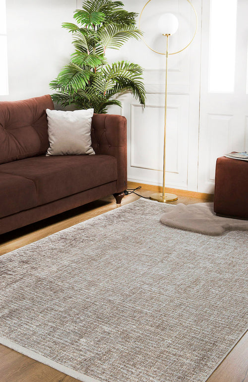Load image 1 in gallery view. A modern living room with a brown sofa, beige pillow, Pure Bliss - Washable Rug - JR745 (Outlet) US for high-traffic areas, potted plant, floor lamp with round shade, and white walls with windows.