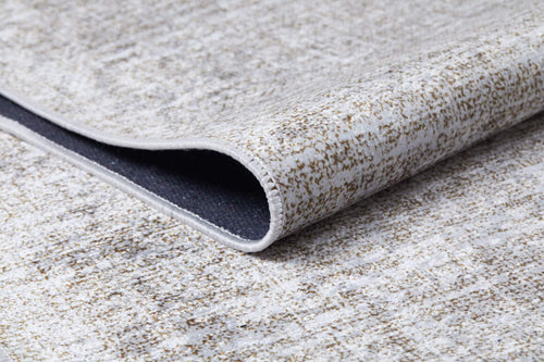 Load image 1 in gallery view. A close-up of the Pure Bliss - Washable Rug - JR745 (Outlet) US shows its cream and beige finish with subtle beige and gray speckles. A folded corner reveals the dark underside and detailed stitching, making it perfect for high-traffic areas.