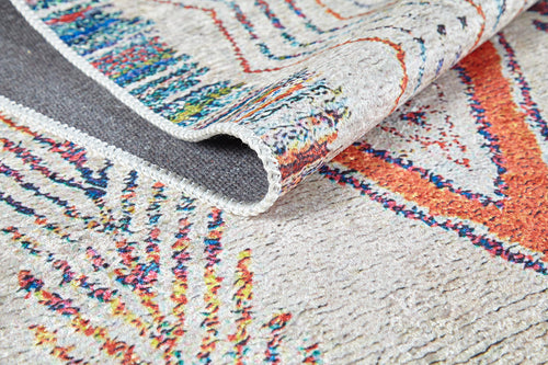 Bild 1 in Galerieansicht laden. A close-up of the Rainbow Rhapsody - Washable Rug - JR5060 shows a folded corner, highlighting its textured flat weave and vibrant orange, blue, and red geometric designs on a beige background.