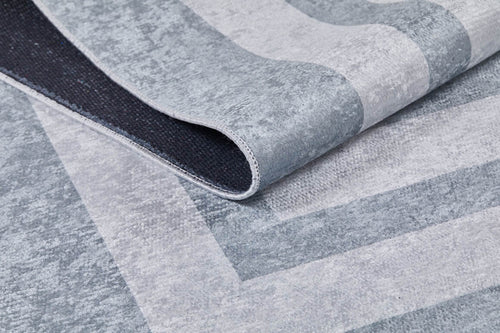 Load image 1 in gallery view. A close-up of Refined Edge - Washable Rug - JR573 in modern gray-anthracite with geometric patterns, partially folded to show its black non-slip backing—durable and ideal for high-traffic areas.