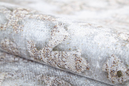 Load image 1 in gallery view. A close-up of the Regal Embellishment - Washable Rug (JR1590) shows a subtle, light gray pattern with brown and beige accents, reminiscent of a gray-anthracite rug. The surface has a slightly metallic or shimmery finish.