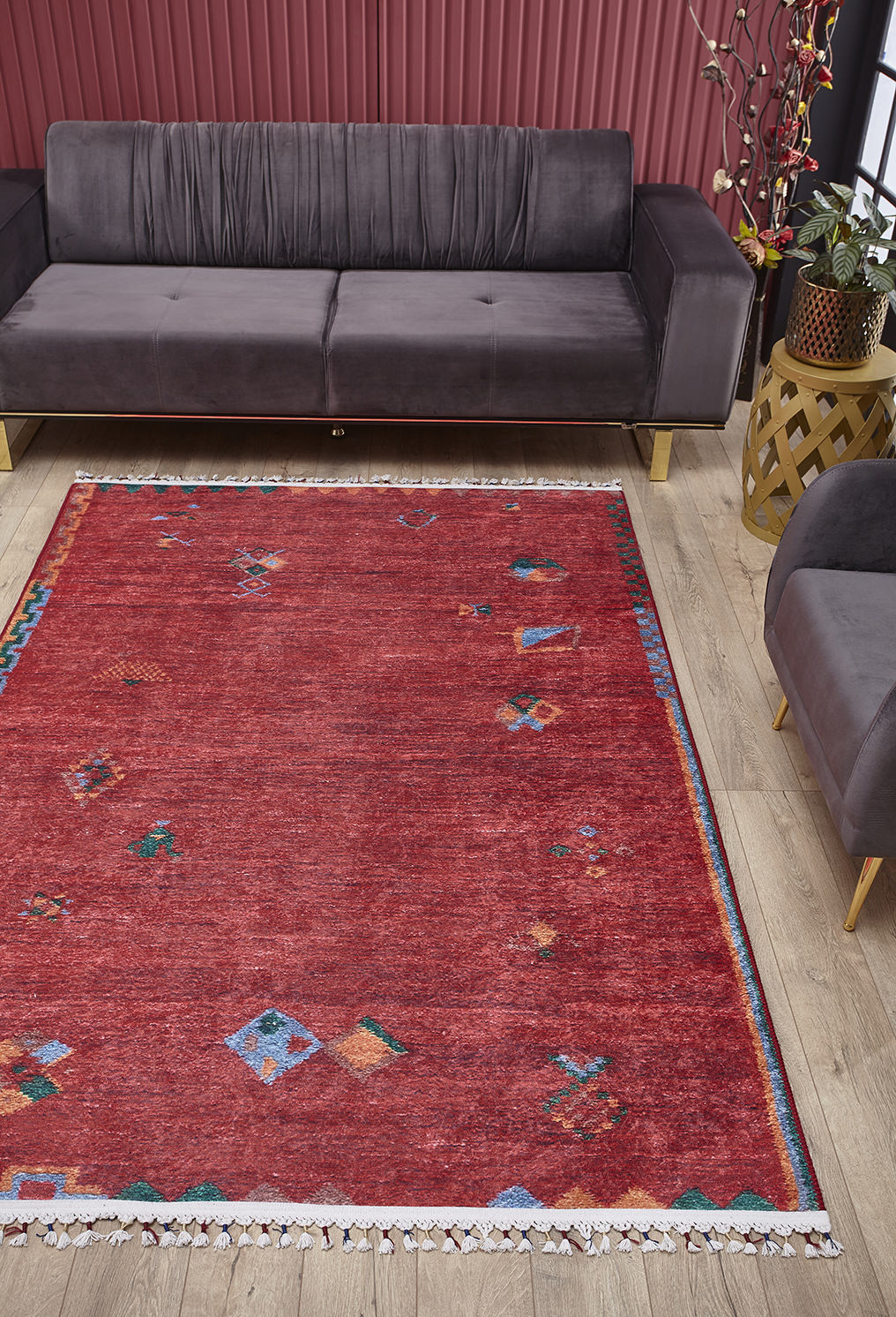 A living room featuring the Rosy Blush - Machine-Washable Rug - JRS5067, perfect for high-traffic areas, gray velvet sofas, a wooden side table with a plant, pink panel walls, light wood floors, and bright natural light.