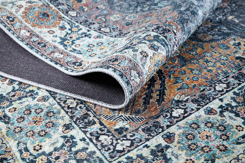 Load image 1 in gallery view. A close-up of the Royal Sultan - Washable Rug - JR1970 showcases its intricate blue, orange, and cream floral-geometric patterns. One corner is folded to reveal the textured underside—perfect for allergy-sensitive homes.