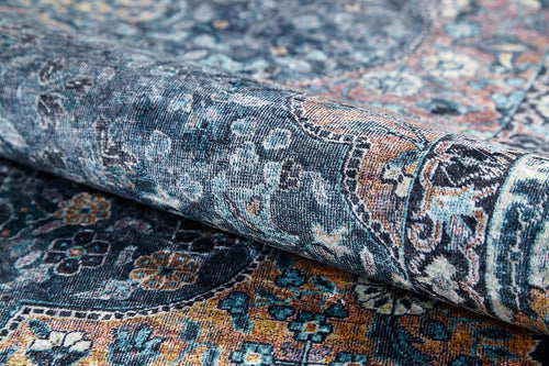 Load image 1 in gallery view. A close-up of the Royal Sultan - Washable Rug - JR1970, rolled up to reveal its detailed floral and geometric patterns in blue, teal, yellow, and orange—perfect for allergy-sensitive homes with its easy-to-clean design.