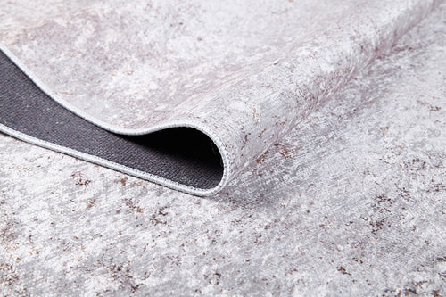 Load image 1 in gallery view. A close-up of the Rustic Trails - Washable Rug - JR1736 shows its textured light gray-anthracite surface and curled edge, revealing a dark non-slip backing—perfect for high-traffic areas.