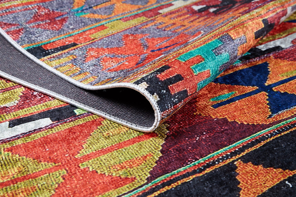 A close-up of the Serene Sahara - Washable Rug - JR1959, featuring multicolor geometric patterns and a folded corner to show its durable front and back textures—ideal for high-traffic spaces.