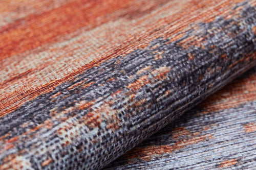 Load image 1 in gallery view. Close-up of the Sleek Brushed - Washable Rug - JR431, displaying its textured woven surface in rust orange, gray, and beige tones with a folded edge—perfect for high-traffic spaces.