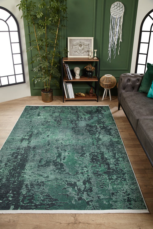Load image 1 in gallery view. A modern living room featuring the Smokey Mountains - Washable Rug - JR1631 in green and black on wooden floors, paired with a gray tufted sofa, dark bookshelf, tall plant, green walls, large arched windows, and a wall hanging.