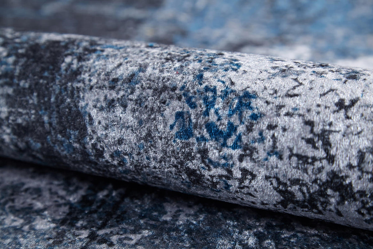 A close-up of the Solar Eclipse - Washable Rug - JR1921 displays its blue and gray mottled velvet texture—soft, plush, and patterned—making it perfect for high-traffic areas and easy to clean.
