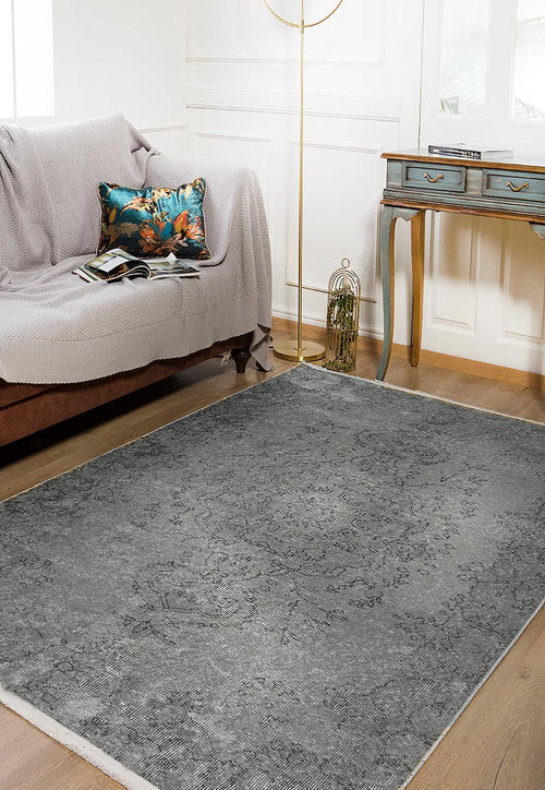 Load image 1 in gallery view. A cozy living room with a brown sofa, a gray throw, a colorful cushion and book, wooden flooring, a blue vintage desk, a gold floor lamp beside a birdcage, and the Sophisticated Design - Washable Rug - JR173 in gray-anthracite.