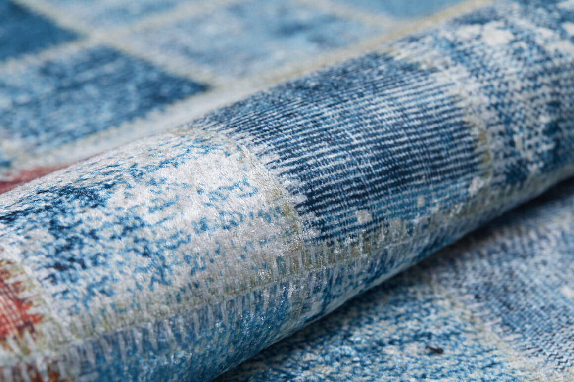 A close-up of the Square Serenity - Washable Rug - JR1255 reveals textured blue fabric with subtle linear patterns, hints of white and red, and a woven, slightly distressed finish—ideal for high-traffic areas.