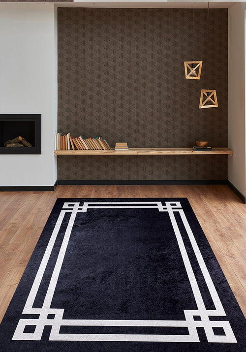 Load image 1 in gallery view. A modern living room showcases the Subtle Border - Washable Rug - JR597 in black with white borders on wood floors, paired with geometric pendant lights, a floating bookshelf, a patterned brown accent wall, and a built-in fireplace—great for busy spaces.