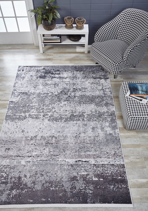 Load image 1 in gallery view. A modern living room with a large Techno Flux - Washable Rug - JR1814 in gray-anthracite, a houndstooth-patterned chair and ottoman, white console table with plants and decor, and light wood flooring.