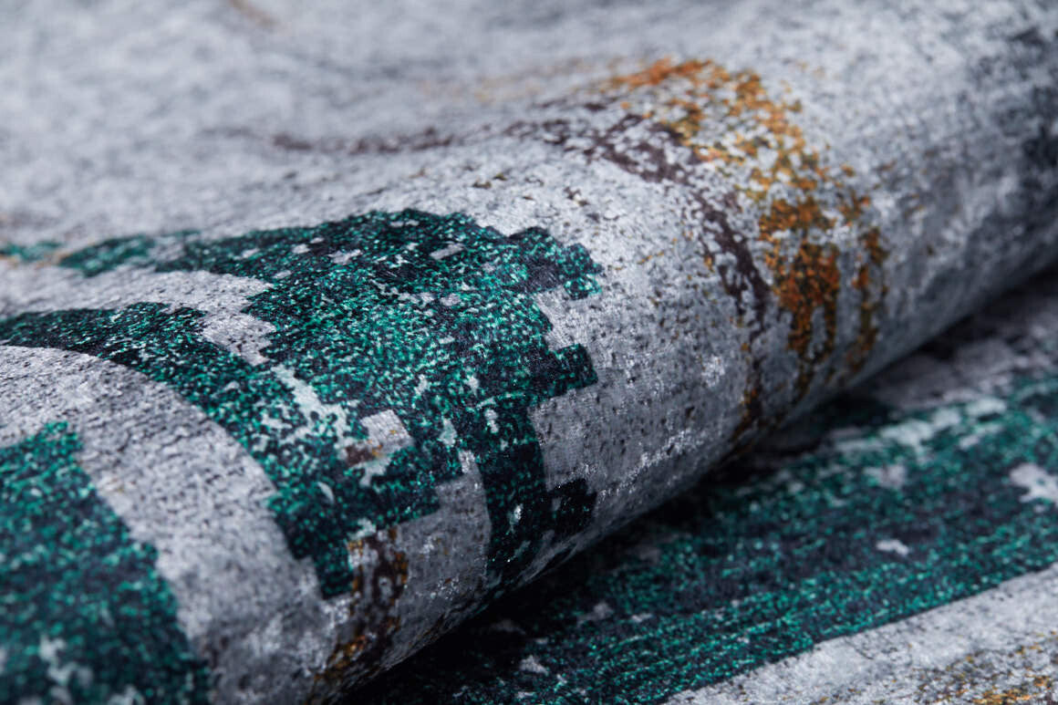 A close-up of the Traditional and Classic - Washable Rug - JR1543 shows teal, green, and gold accents on a gray flat weave with allergy-friendly fabric that's slightly folded, highlighting its vibrant colors.