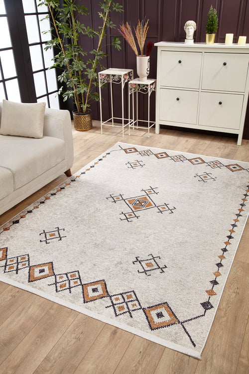 Load image 1 in gallery view. The Tribal Tassel - Washable Rug - JR1683, in cream and beige with geometric patterns, enhances a cozy living room featuring a beige sofa, white cabinet, plants, and décor—ideal for high-traffic wooden floor spaces.