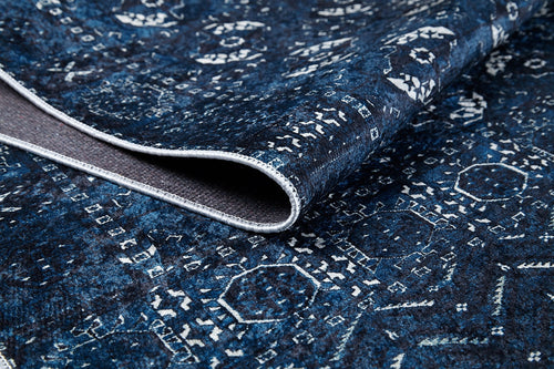 Load image 1 in gallery view. A close-up of the Tribal Trail - Washable Rug - JR1939 in blue and white, featuring intricate geometric patterns with a curled edge exposing the underside and texture—ideal for high-traffic spaces.