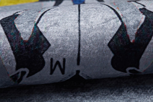 Load image 1 in gallery view. Close-up of the Turbo Tracks - Machine-Washable Rug JRC089: a textured gray-anthracite surface with black shapes, the letter M, and symmetrical black, white, and blue patterns—ideal for high-traffic areas.