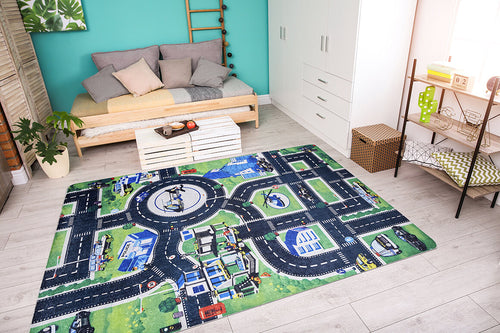 Load image 1 in gallery view. A bright, modern living room with a gray sofa, pastel cushions, wooden coffee table, white cabinets, and the Urban Road - Machine-Washable Rug JRC013 featuring roads, buildings, and cars on a light wood floor.