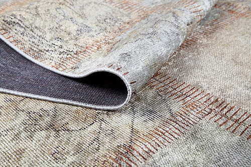 Load image 1 in gallery view. A close-up of the Urban Utopia - Washable Rug - JR1957 shows its folded corner, revealing a dark underside and stitched edges. This flat weave rug features muted beige, gray, and brown tones in a grid-like pattern.