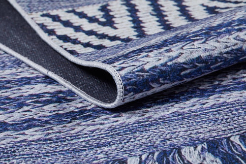 Load image 1 in gallery view. A close-up of the Wavy Wonders - Washable Rug - JR941, featuring folded edges and intricate geometric zigzag patterns in blue and white—durable and detailed for high-traffic areas, highlighting its textured fabric.