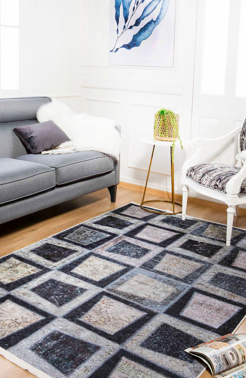 Load image 1 in gallery view. A modern living room with a gray sofa, white armchair, small round side table with a plant, abstract artwork, and the Windowpane Wonder - Washable Rug - JR184 in a geometric pattern on the wooden floor.