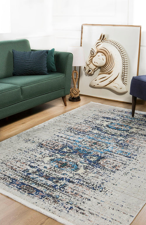 Load image 1 in gallery view. A modern living room with a green sofa, blue pillow, the Worn-Out Abstract - Washable Rug - JR339 in blue and gray for high-traffic areas, a floor lamp, and a large framed horse relief leaning against the wall.