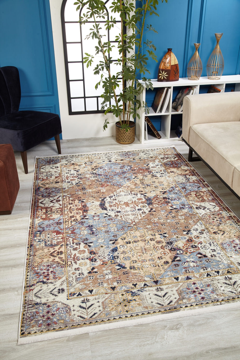 The Native Nature's - Washable Rug - JR1666 adds vibrant pattern to a modern living room with light wood floors, blue walls, a beige sofa, black chair, potted plant, and decor on a white console.
