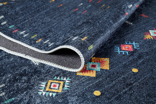 Load image 1 in gallery view. A close-up of the Wanderer's Way - Washable Rug - JR5101 in dark blue, featuring colorful geometric patterns and a stitched white edge. This textured, washable rug is slightly folded—perfect for high-traffic areas.